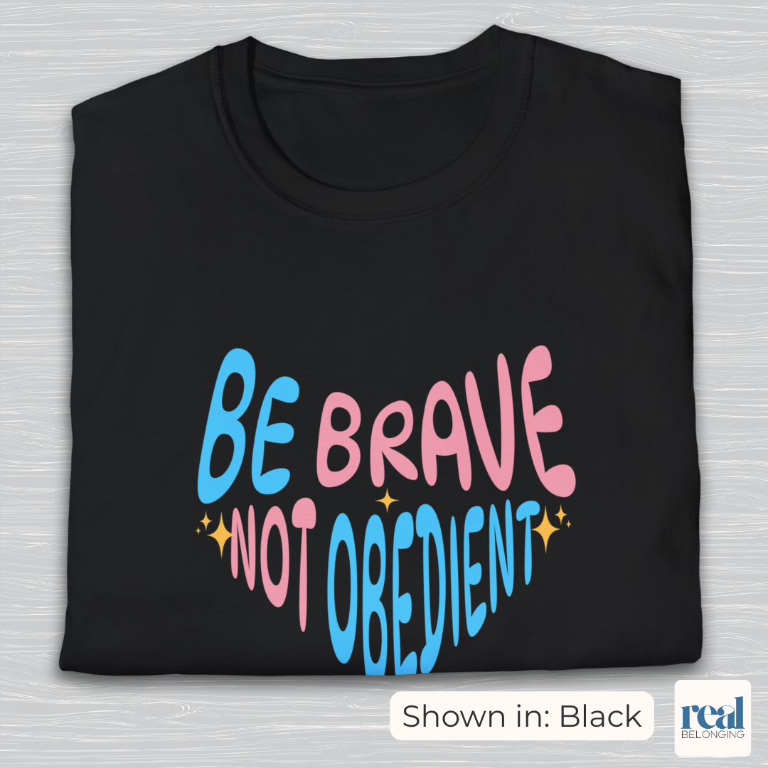 Be Brave, Not Obedient in transgender pride blue and pink colors on black t-shirt folded