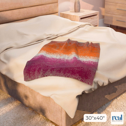 Colorful blanket on a bed with a visible brand logo in the corner.